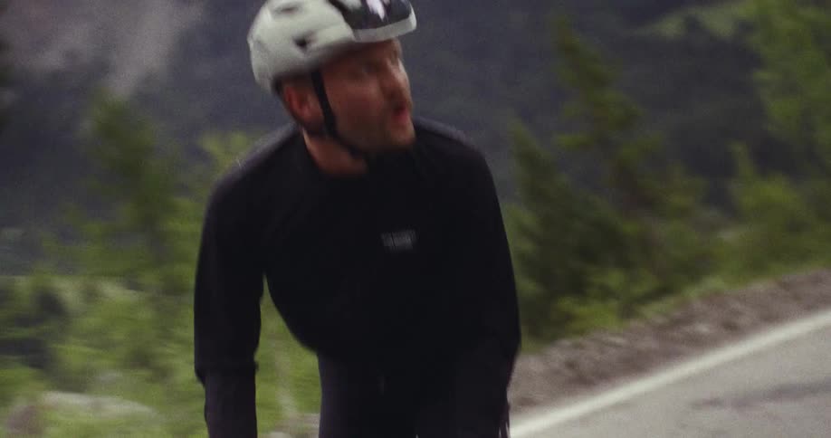 The man is pedaling his bike uphill