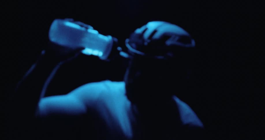 A man riding a bike and pouring water on his face