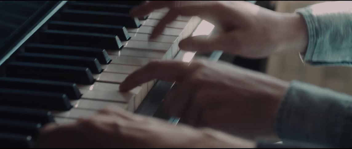 A closeup view captures the nimble movements of a pianists hands as they rhythmically press against the black and white keys playing a melody in a softly lit setting
