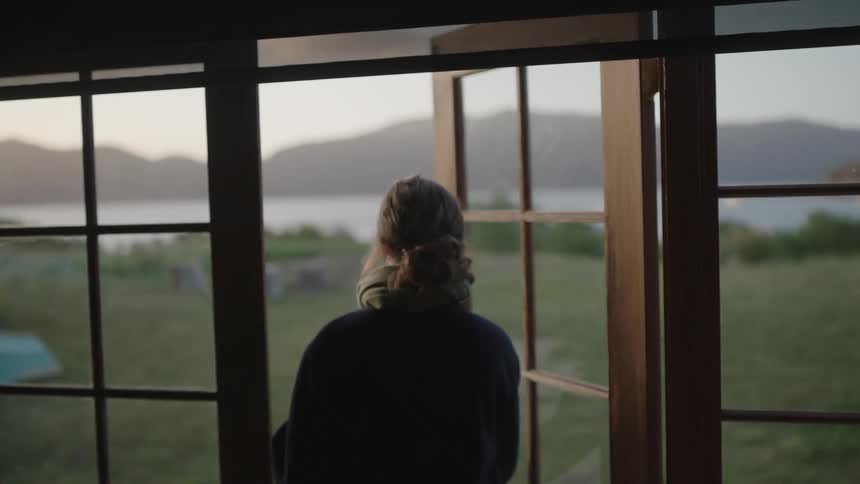 The woman exits her home to walk in her yard