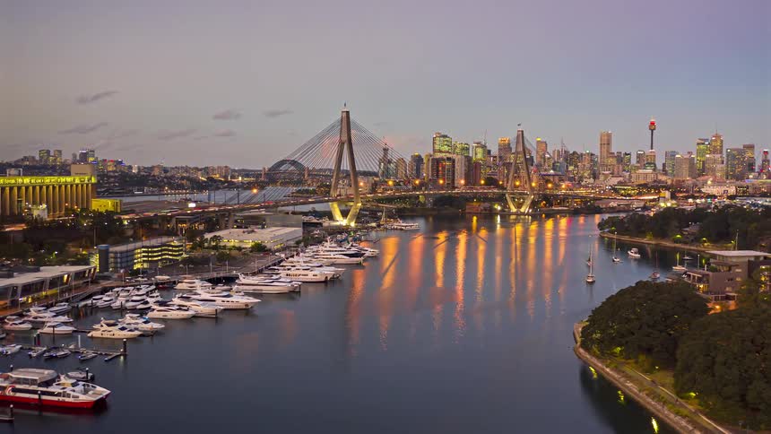 Boats in the marina and sailing on the water as traffic moves across the bridge with city buildings in the distance