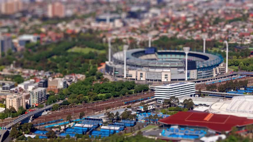 Traffic is moving on a highway through a city next to a stadium