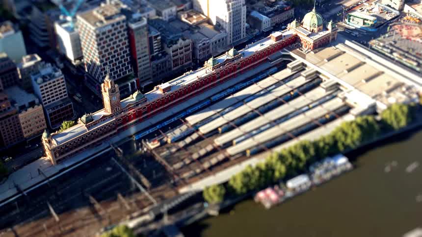 Shadows sweep across a city train station and its platforms in a toy like miniature scene