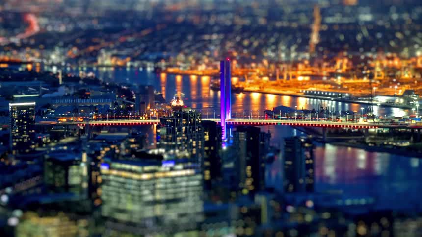 Glittering city lights and an illuminated bridge sparkle in this nighttime aerial view