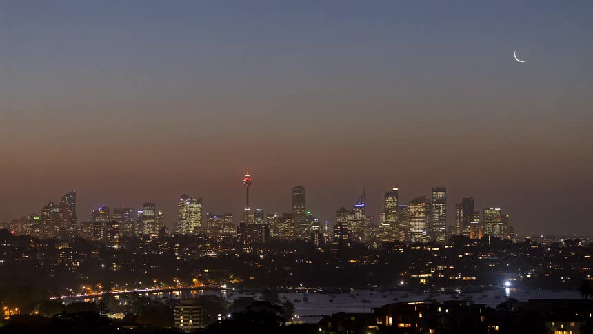Aerial view of a metropolitan city skyline overlooking a harbor at sunset
