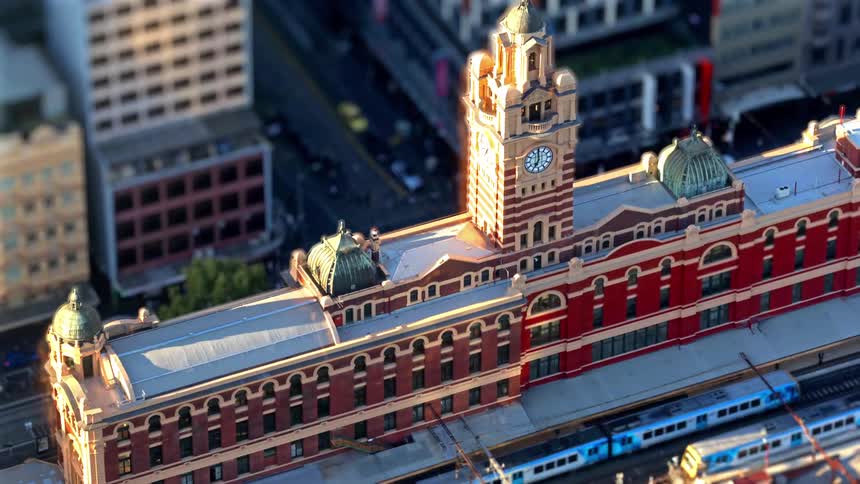 Historic building with a clock tower and domes above a railway station in an urban area