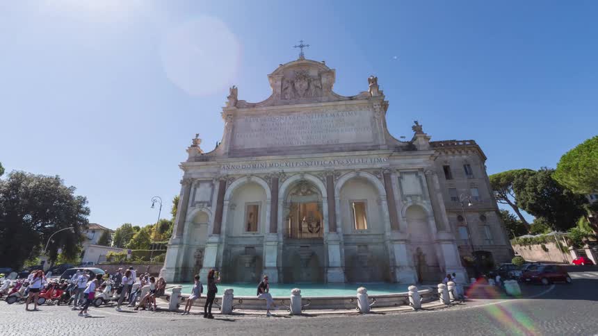 Monumental stone faade with arches and inscriptions people gathered in the square under a clear sky