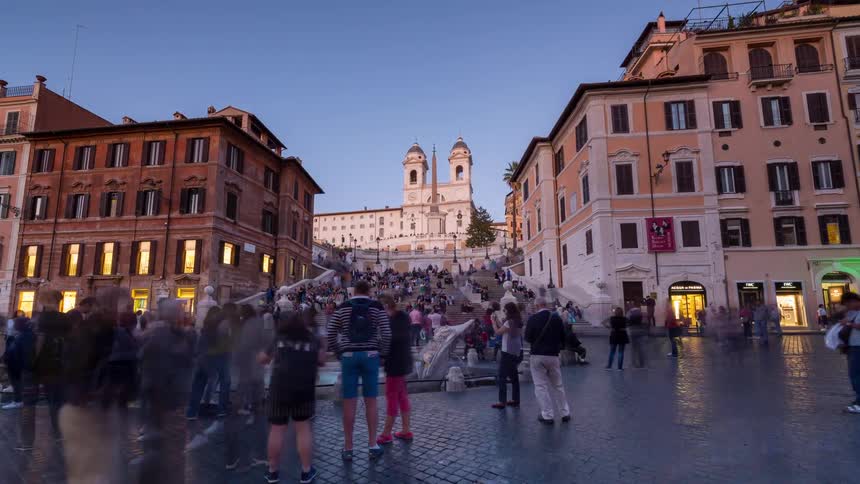 A large crowd walking in a busy city street from daylight to nighttime surrounded by residential buildings