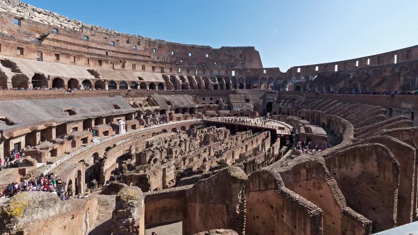 Many people walking inside the colosseum in rome as they tour the ancient structure and landmark