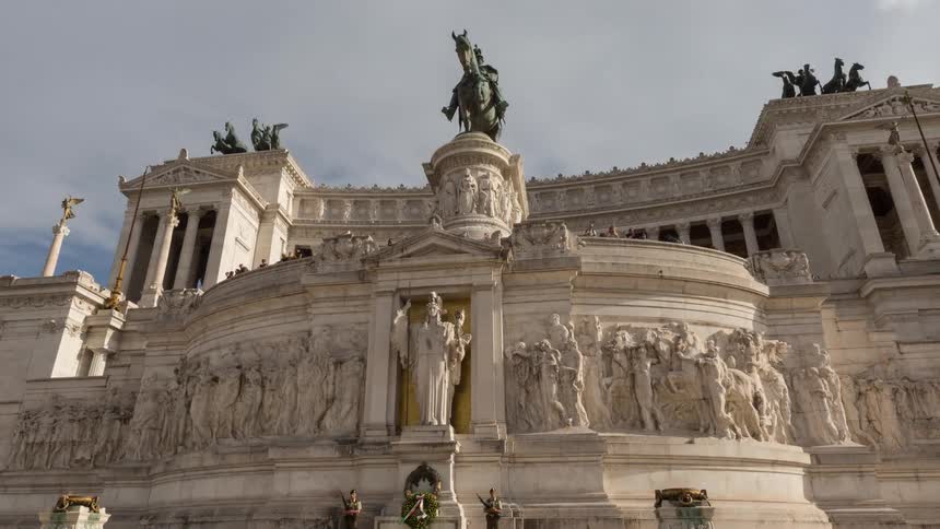 Historic monument with relief sculptures colonnades and an equestrian statue under a partly cloudy sky