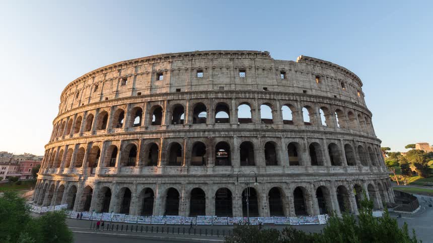 Cars drive past ancient ruins of a stadium