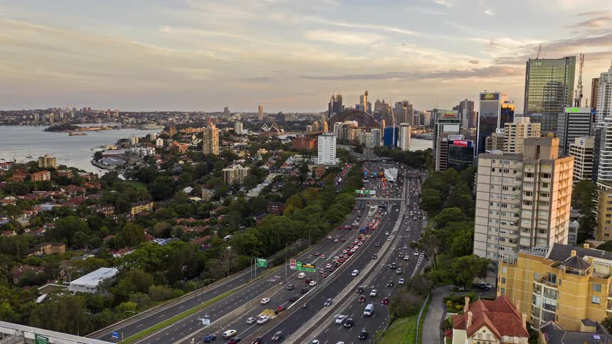 Aerial view of an urban area with a busy expressway green spaces and a skyline in the background at dusk