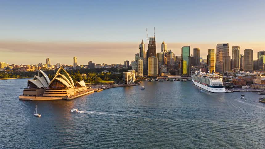 Boats move in and out of the port next to an opera house