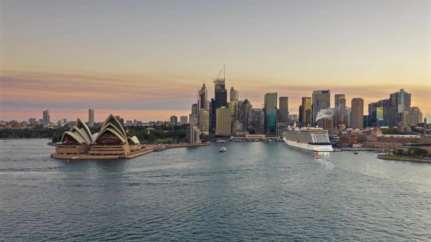 Boats and ferries traverse sydney harbor at dusk set against the backdrop of the opera house and city skyline