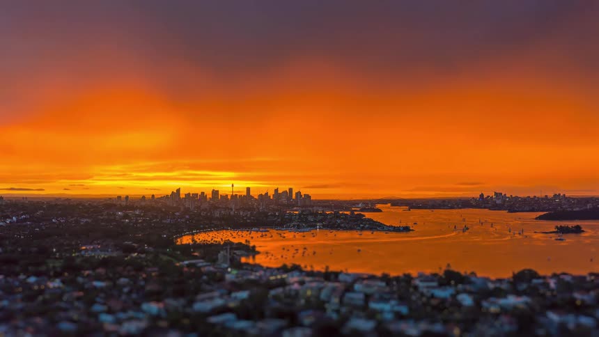 Sunset over the bay with the city skyline in the background and boats scattered across the water