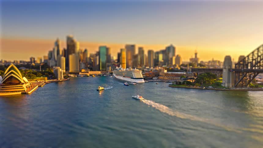 Watercraft moving past the sydney opera house leave wakes as the sun sets