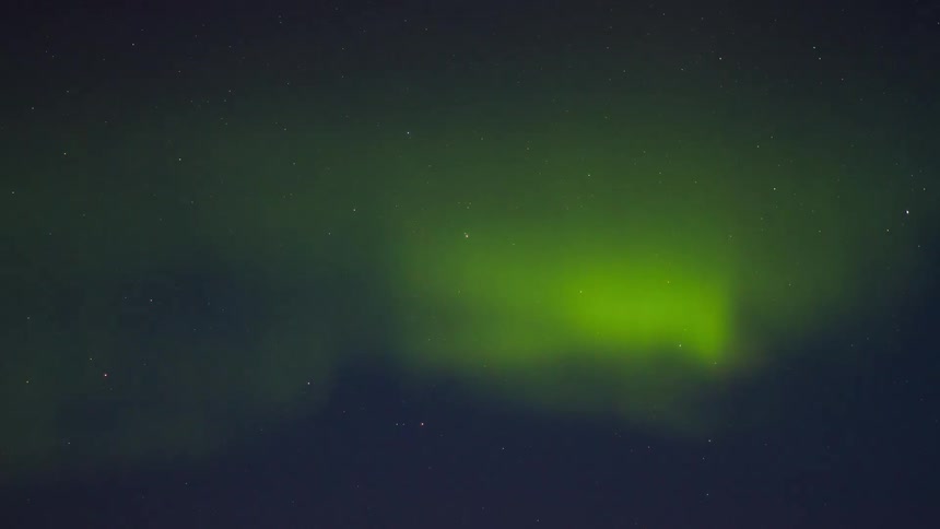 Northern lights forming green luminous bands under a starry night sky