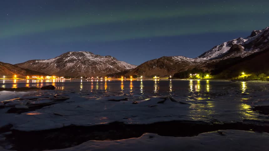 The aurora flows over the lake and mountains