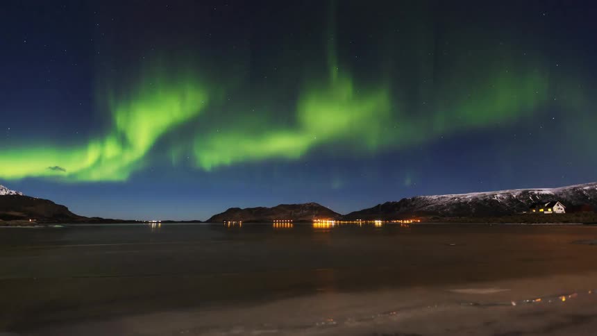 Northern lights move above a small lakeside town