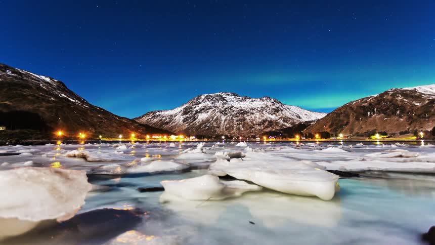 Large pieces of ice are floating in the water of a coastal town in the mountains