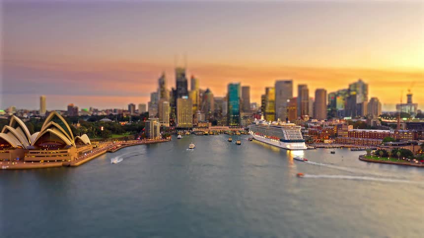 Urban bay at dusk with a cruise ship moving boats and a skyline in the background