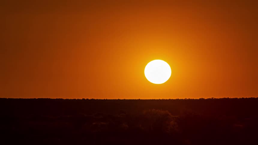 Sun sets over the landscape in a deep orange sky