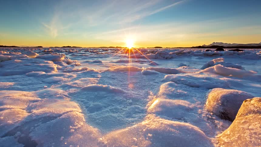 Low sun on the horizon illuminating a frozen surface with scattered ice blocks