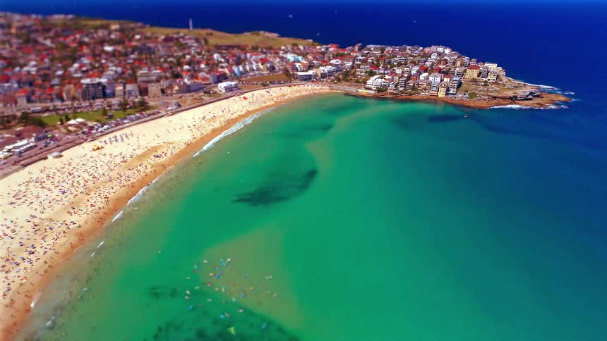 Coastal community with people on the beach and in the water as waves roll in to shore