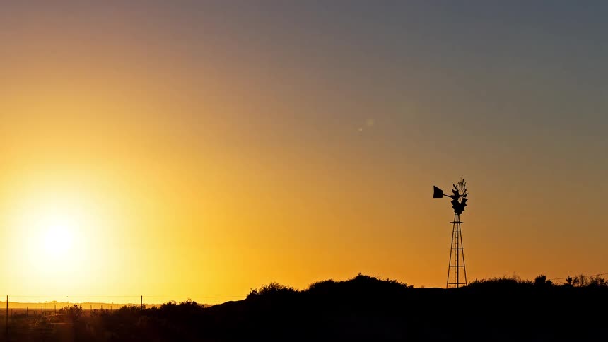 The rising sun lights up a windmill