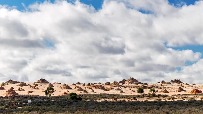 A vast landscape with hills and green vegetation under a midday sunny sky covered with white clouds