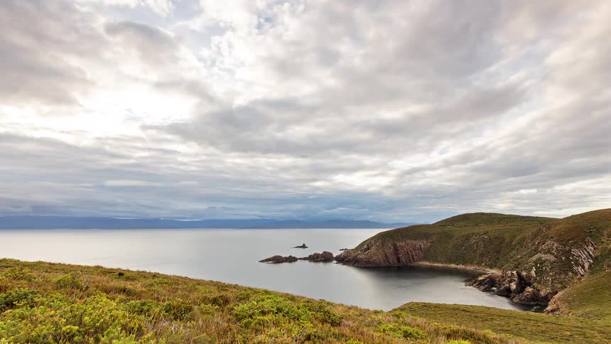 The clouds are flowing over the green shore