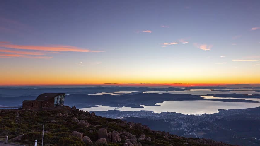 Sunrise over a mountainous landscape with a lookout on the left lakes and valleys in the background