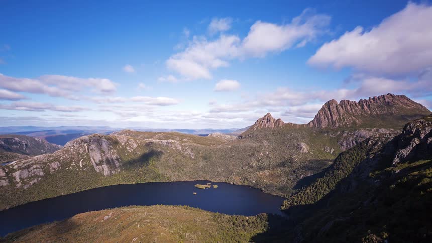 Clouds passing over a river and the nearby mountains cast shadows