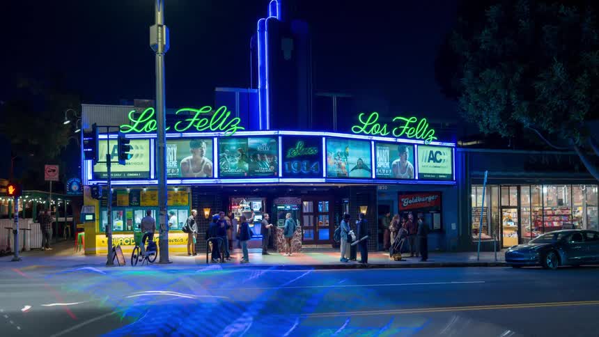 The glowing neon signs of a theater in Los Angeles as the historic art deco building showcases its classic movie marquee against the dark night sky