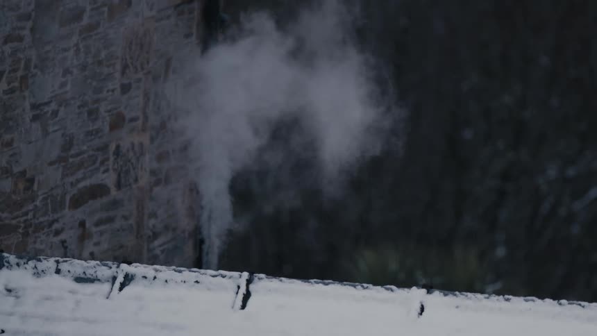 Steam rising from a snowcovered surface next to a stone wall in a cold environment
