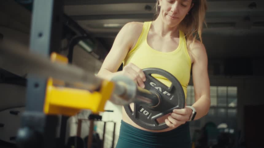 A woman loading plates onto a bar