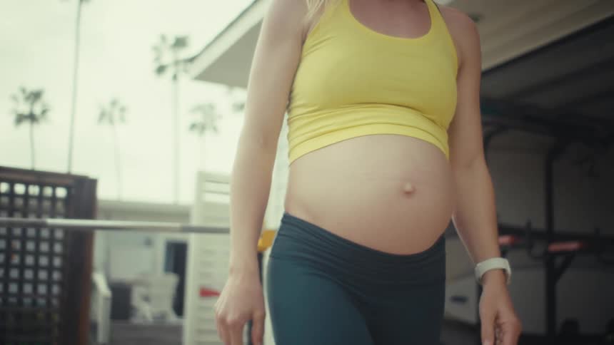 Pregnant woman performing a bench press exercise with a barbell on a weight bench