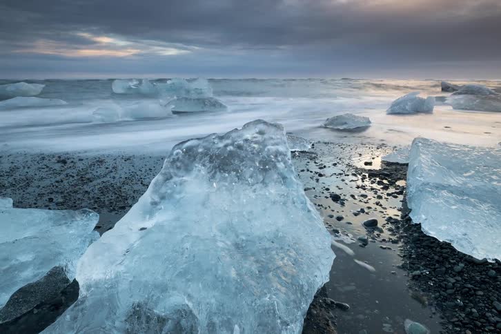 Melting ice along the coast as waves roll into shore