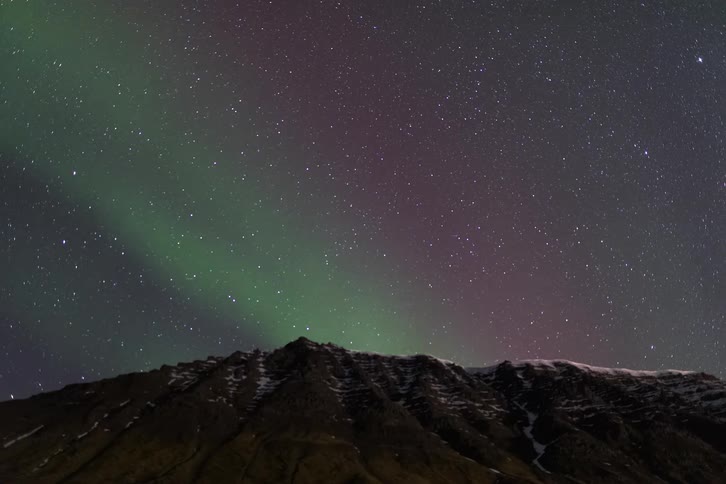 Northern lights above a mountain range with a starfilled night sky