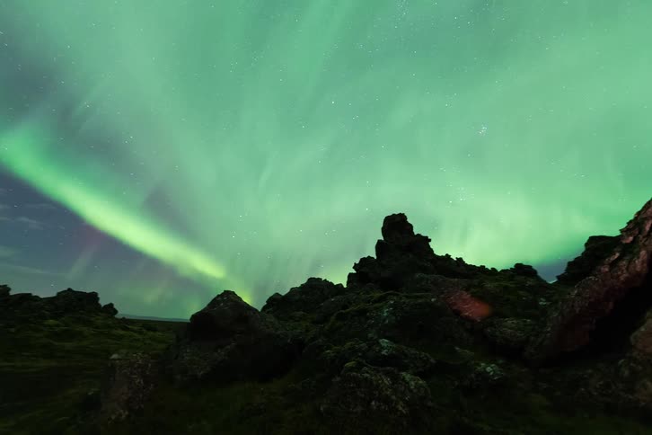 A view of a landscape with aurora above it