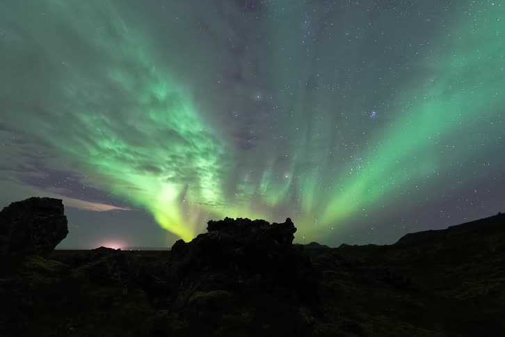 A view of a landscape with the aurora above it