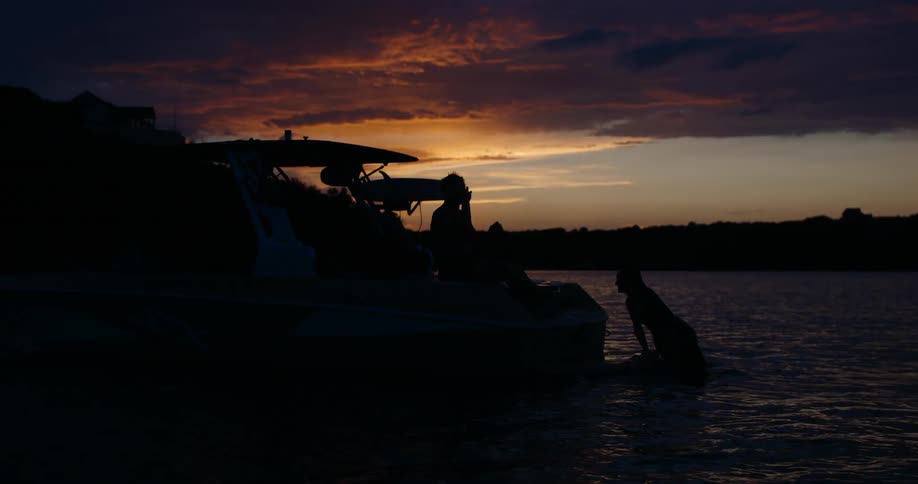 Two people swimming off the back of a boat