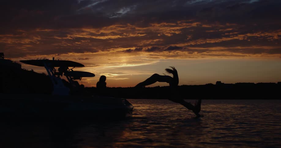 Two women diving off a boat into the water