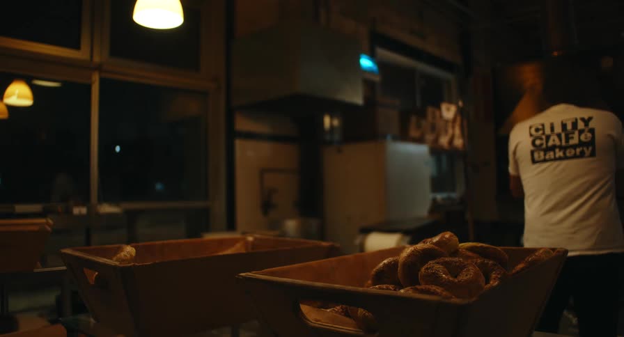 Baker working baking in the oven with fresh bagels on the table