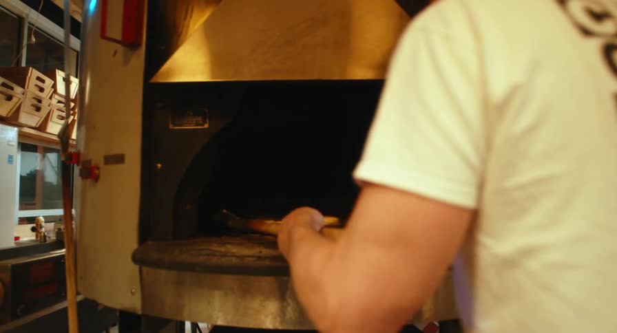 Baker pulls a tray of bagels out of the oven