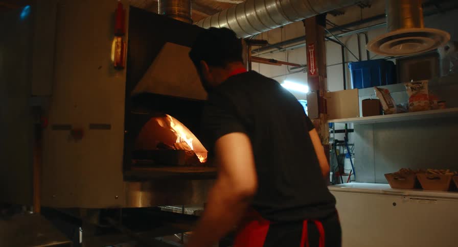 The man is stirring wood in the kitchen wood fired oven