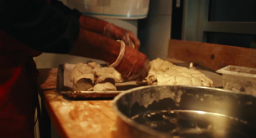 Manual bread preparation with dough portions aligned on a work surface