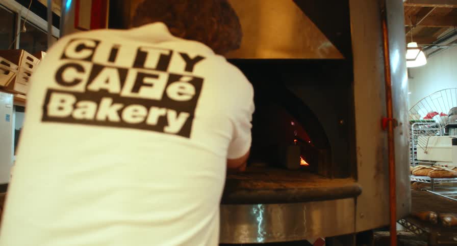 A person taking food out of a large wood oven