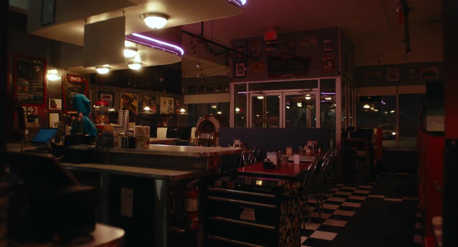 Retro diner interior with a counter arranged tables artificial lighting and a checkered floor