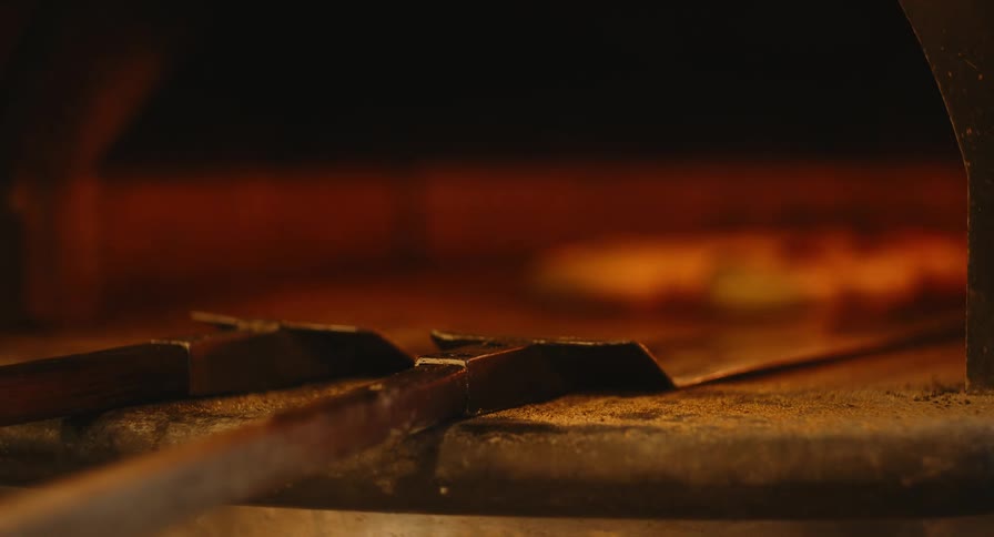 Long wooden peels rest at the opening of a hot glowing oven
